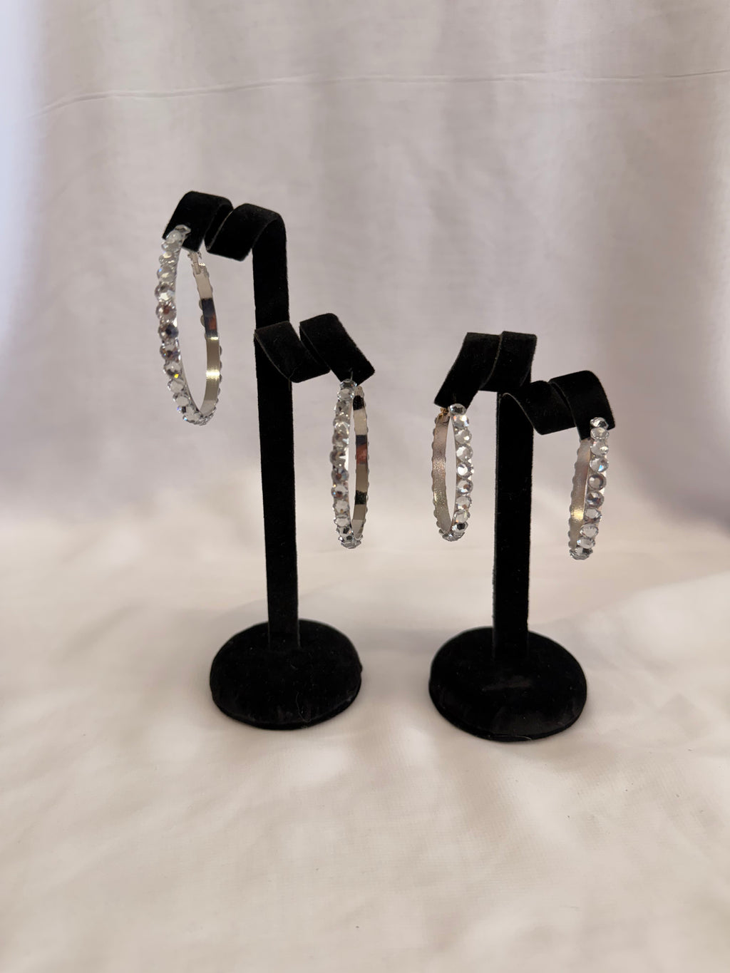 Empress Collection skinny hoop earrings featuring precision-cut Crystal AB Austrian crystals on a high-gloss black display stand
