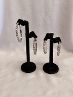 Empress Collection skinny hoop earrings featuring precision-cut Crystal AB Austrian crystals on a high-gloss black display stand