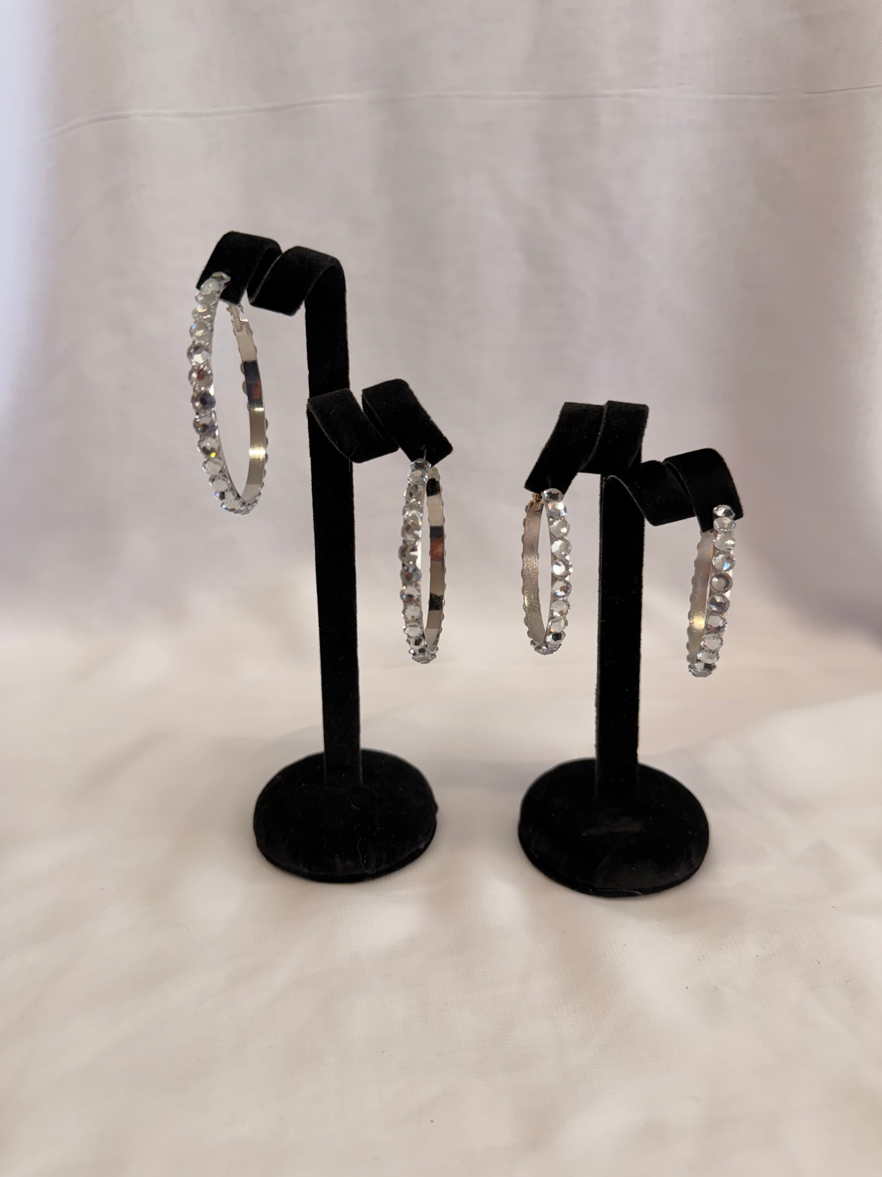 Empress Collection skinny hoop earrings featuring precision-cut Crystal AB Austrian crystals on a high-gloss black display stand