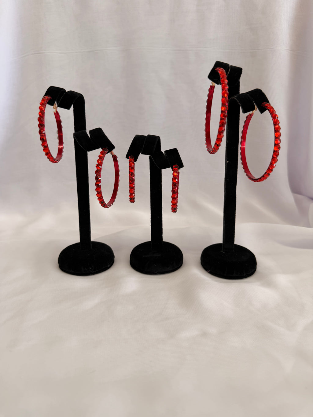 Aurora Collection Siam Red skinny hoop earrings featuring vibrant red performance crystals on a black velvet jewelry display.