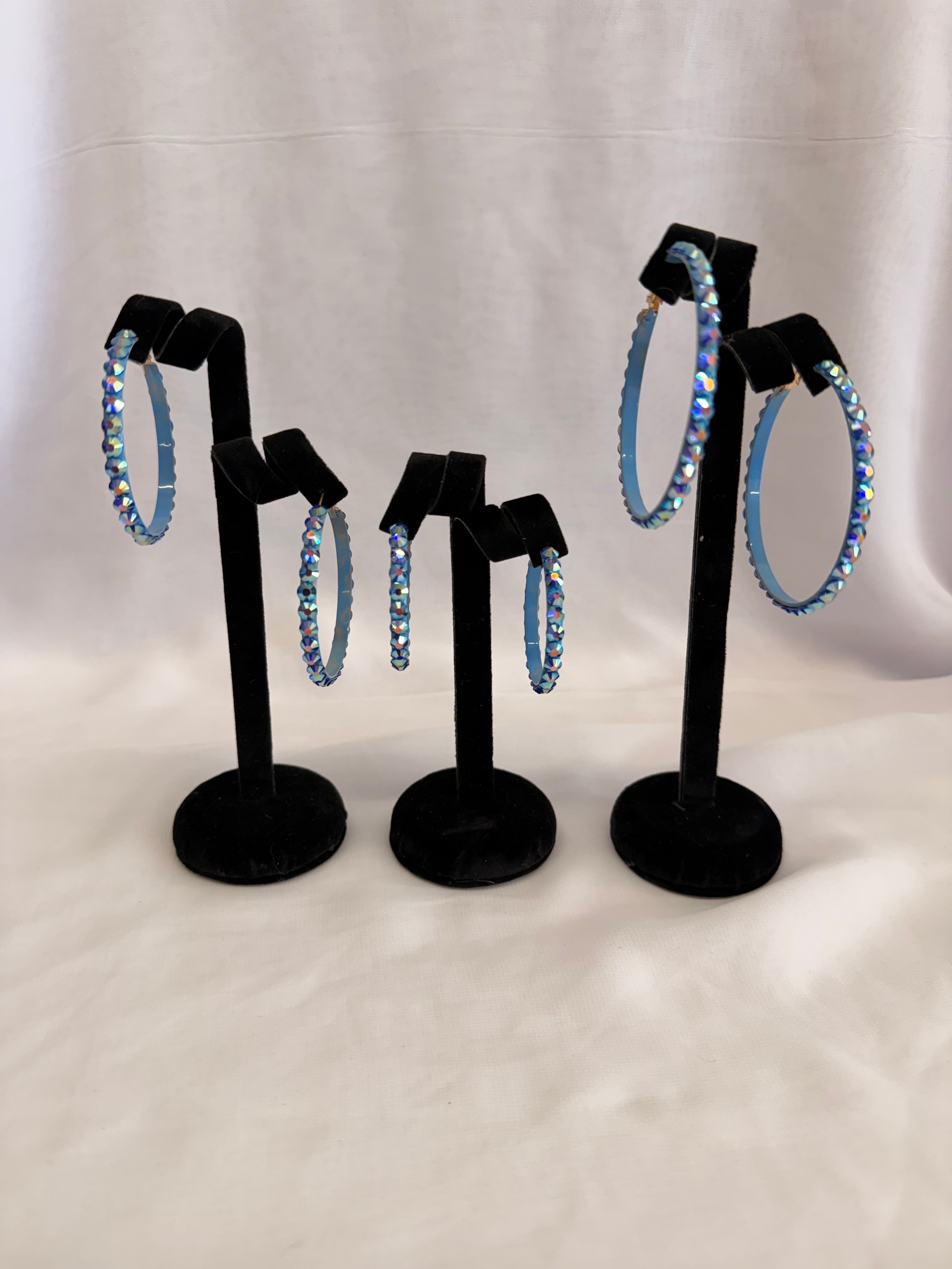 Aurora Collection Blue Zircon AB skinny hoop earrings for ballroom dance featuring iridescent teal Austrian crystals on a black display stand.